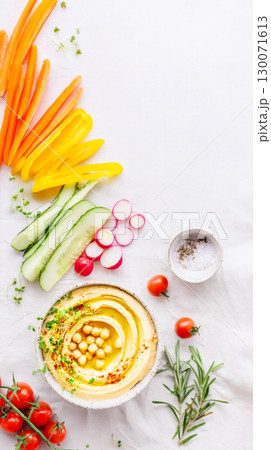 Rainbow Vegetable Sticks With Classic Hummus Dip On White Tabletop. Concept Of Healthy Snacking, Plant-Based Diet, And Bright Clean Food Styling For Modern Nutrition Content Rainbow Vegetable Sticks With Classic Hummus Dip On White Tabletop. Concept Of Healthy Snacking, Plant-Based Diet, And Bright Clean Food Styling For Modern Nutrition Content 130071613