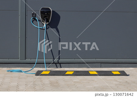 Modern electric vehicle charger on building wall 130071642