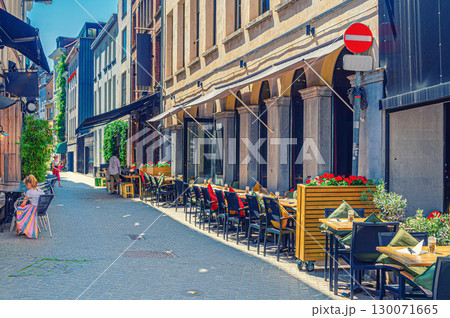 Street restaurant with tables and chairs on narrow street, road with paving stone, old buildings in Antwerp historical city center, street cafe in old town Antwerpen, Belgium Street restaurant with tables and chairs on narrow street, road with paving stone, old buildings in Antwerp historical city center, street cafe in old town Antwerpen, Belgium 130071665