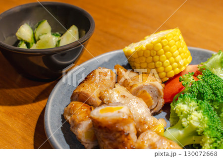 豚肉の野菜巻きとトウモロコシや野菜、きゅうりの副菜を添えた夕食 豚肉の野菜巻きとトウモロコシや野菜、きゅうりの副菜を添えた夕食 130072668