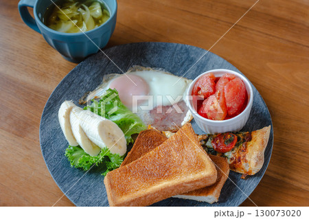 トーストや目玉焼き、バナナやトマト、ピザを盛り付けた洋風朝食プレート 130073020