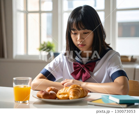 寝不足で朝の食卓で食欲がなく元気がなく下を向く女子中学生 130073053