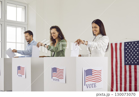 American citizens standing in a row at polling station and putting their ballots in voting booth. American citizens standing in a row at polling station and putting their ballots in voting booth. 130073070