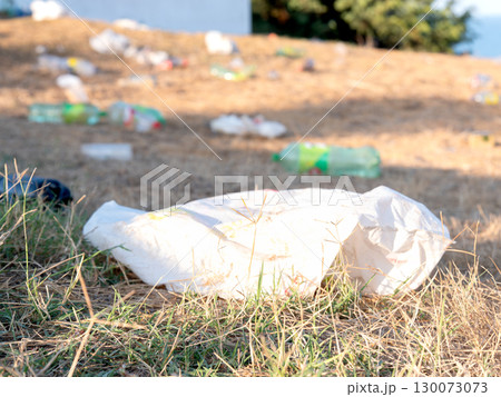 Littered plastic waste on a grassy field near a beach 130073073