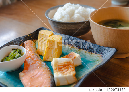 焼き鮭と卵焼き、かまぼこと小鉢を添えたご飯と味噌汁の和風朝食 130073152