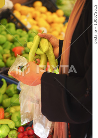 Woman selecting fresh peppers at outdoor market Woman selecting fresh peppers at outdoor market 130075615