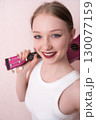 Young female musician holding ukulele by neck and slinging musical instrument over shoulder, she's feeling inspired. Beautiful woman looking camera with smile, positive attitude and happy expression 130077159
