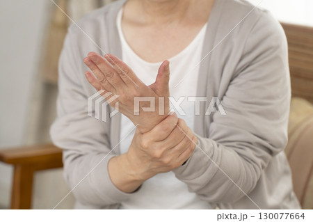 手の痛みこわばりに悩むシニア女性の手 130077664