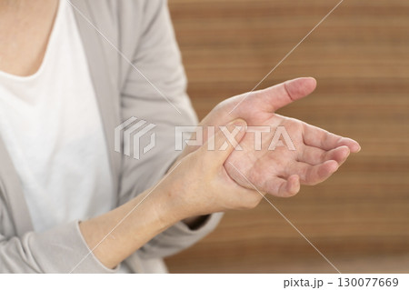 手の痛みこわばりに悩むシニア女性の手 130077669