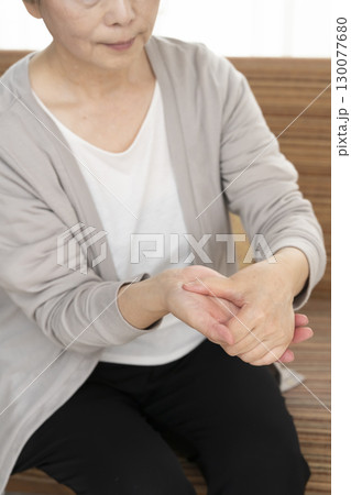手の痛みこわばりに悩むシニア女性の手 130077680