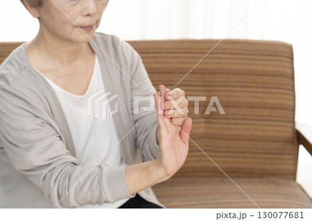 手の痛みこわばりに悩むシニア女性の手 130077681