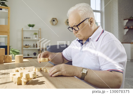 Senior man playing with jigsaw puzzle to prevent dementia and Alzheimer's disease 130078375