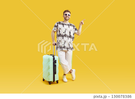 Young man in sunglasses with suitcase is going on summer holiday on yellow background. 130078386