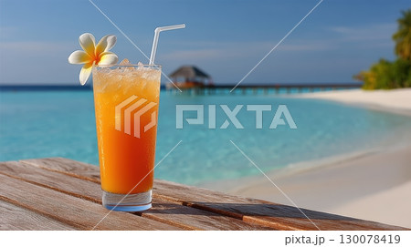 Refreshing Vibrant Tropical Cocktail on Table by the Beach with Clear Blue Water and Palm Trees 130078419