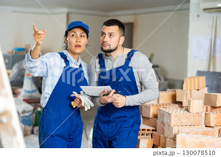 Male and female contractors with papers discussing in building during renovation Male and female contractors with papers discussing in building during renovation 130078510