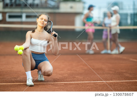 Smiling young female tennis player posing after game on outdoor court 130078607