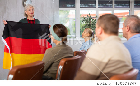 Female tutor showing flag of Germany leading language club for elderly Female tutor showing flag of Germany leading language club for elderly 130078847