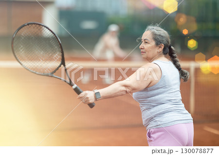 Sporty senior woman playing tennis with female opponent outdoors 130078877
