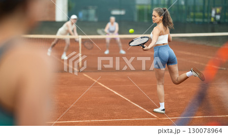 Emotional fit young girl playing doubles tennis on outdoor court Emotional fit young girl playing doubles tennis on outdoor court 130078964