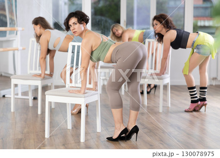 Woman practicing modern stiletto choreography with chair during group class 130078975