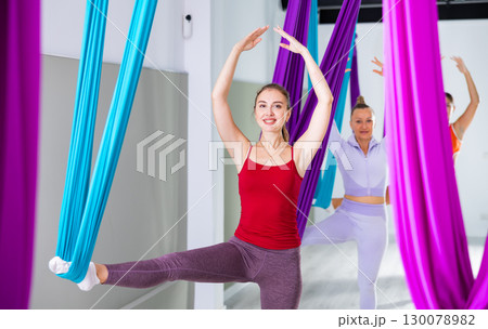 Group of beautiful yoga women doing aerial yoga practice in hammocks in fitness club Group of beautiful yoga women doing aerial yoga practice in hammocks in fitness club 130078982