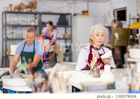 female potter paints finished vase in white 130079004