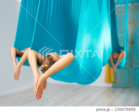Woman pose in hammock performing aerial yoga or flying yoga 130079009