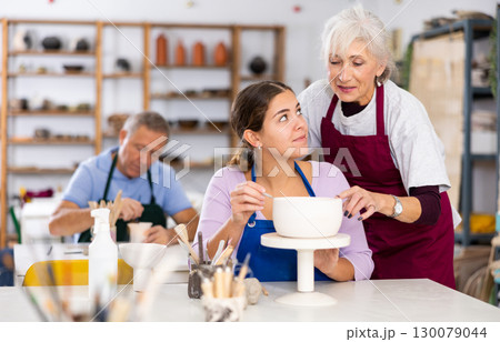 Professional female potter teaches young woman to create pottery 130079044