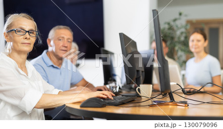 Old woman learning computer programs in training room 130079096