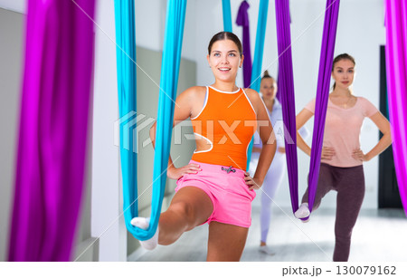 Young yoga woman doing aerial yoga practice in hammock in fitness club 130079162