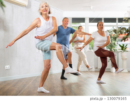 Group of mature sports women and man in activewear exercising dynamic dancing movemens in modern gym studio 130079165