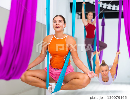 Young woman performing antigravity yoga exercise in gym Young woman performing antigravity yoga exercise in gym 130079166
