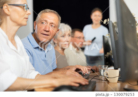 Computer lessons for elderly people in nursing home. Group of seniors learning to use computers in class 130079253
