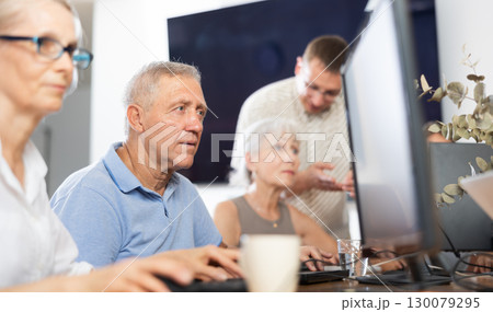 Focus on senior man who is learning to work on computer in group of elderly people Focus on senior man who is learning to work on computer in group of elderly people 130079295