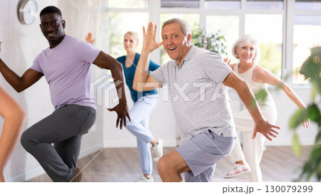 Positive senior man practicing vigorous dance during group class Positive senior man practicing vigorous dance during group class 130079299
