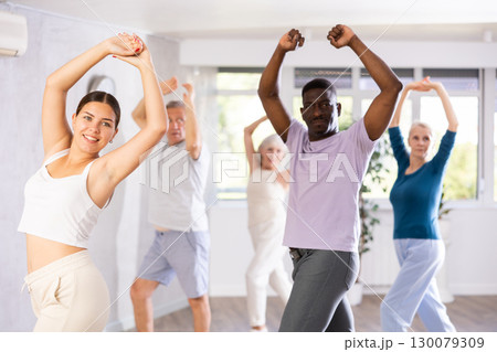 Young female dance instructor practicing flamenco with group of mature people Young female dance instructor practicing flamenco with group of mature people 130079309
