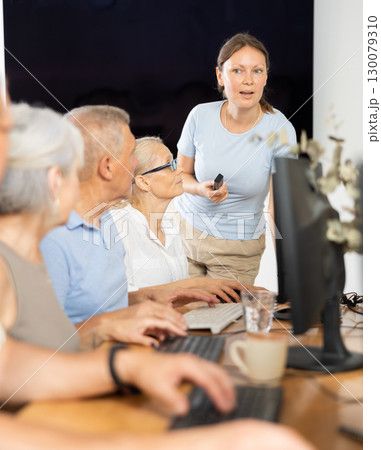 Mature people listen attentively to female teacher during computer teaching lesson in nursing home Mature people listen attentively to female teacher during computer teaching lesson in nursing home 130079310