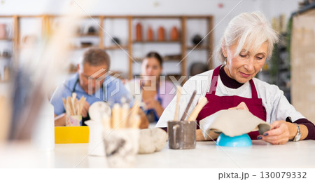 elderly woman is working with billet elderly woman is working with billet 130079332
