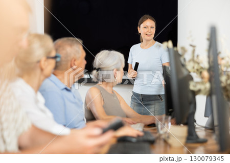Woman teacher teaching elderly people how to use computer Woman teacher teaching elderly people how to use computer 130079345