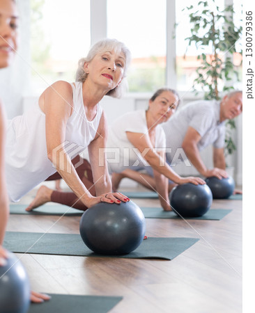 Group of elderly people doing pilates with soft ball in studio 130079386