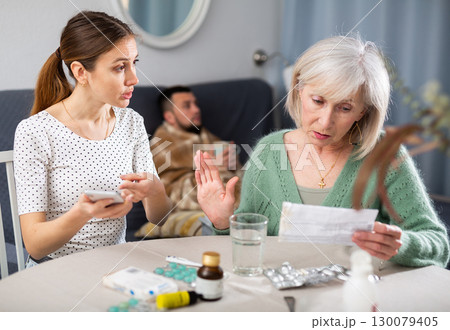 Young wife and an elderly mother discuss what medicines are needed for sick husband Young wife and an elderly mother discuss what medicines are needed for sick husband 130079405