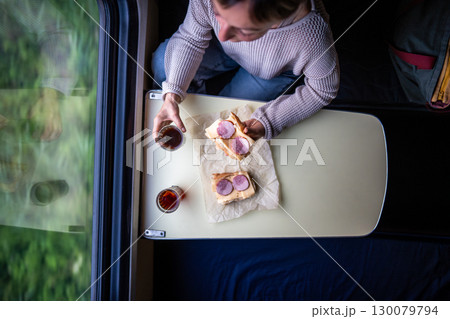 Train lunch, solo woman eating sandwich drinking tea waiting neighbor on travel commute journey 130079794