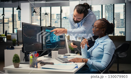 Teamworking proprietary firm colleagues using deep learning to assess stock market volatility. Brokerage company supervisor and african american woman using AI to generate investment reports 130079903