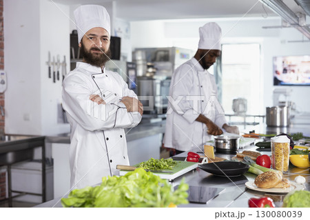 Head chef in uniform and hat preparing gourmet dishes with fresh produce, using culinary tools and stainless steel utensils. Professional cook working in the gastronomy industry. 130080039