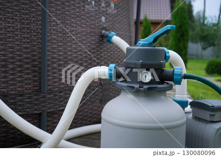 A filtration system for a backyard pool, powered by a pump, situated outdoors on a hot, sunny summer afternoon. 130080096