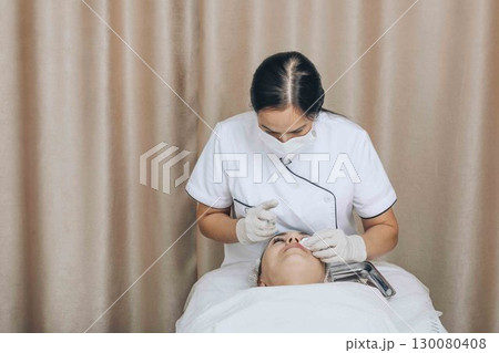 Gentle Enhancements: Showcasing the skillful application of a facial treatment by a professional 130080408