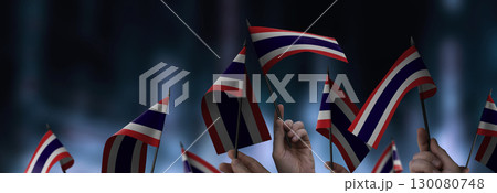 Thailand flags in their hands on a blurred urban background 130080748