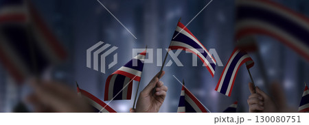 Thailand flags in their hands on a blurred urban background 130080751