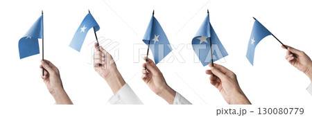 The Somalia flag in hand in different angles on a white background 130080779