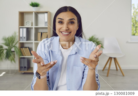 Young brunette woman sitting at home looking at the camera having online video call. Young brunette woman sitting at home looking at the camera having online video call. 130081009
